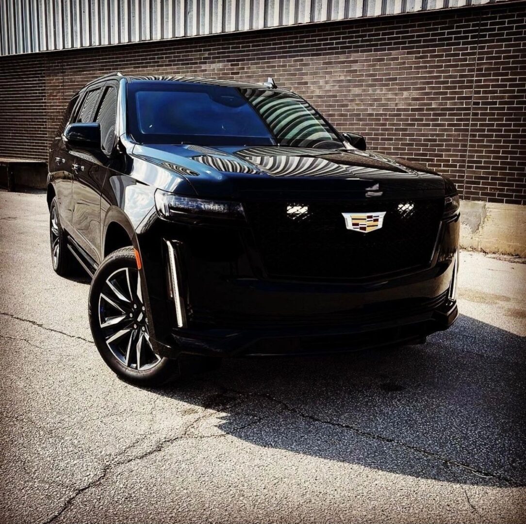 A black car parked in front of a brick wall.