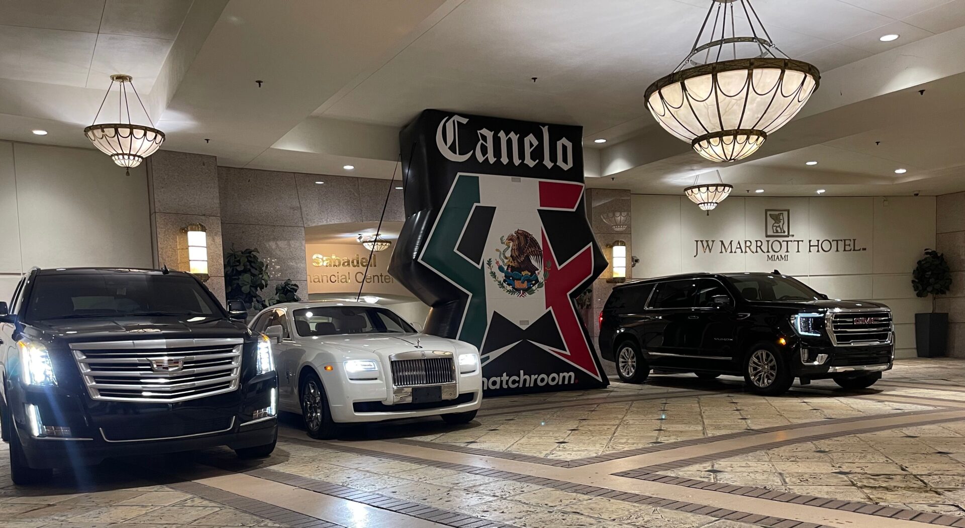 A couple of cars parked in front of a large sign.