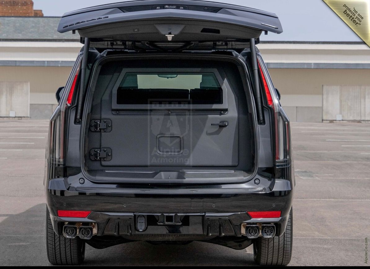 A black suv with its trunk open parked on the street.