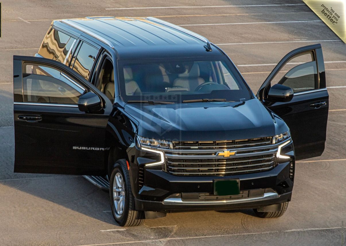 A black suv parked in the parking lot with two cars.