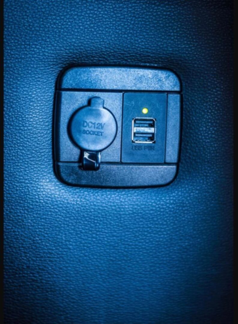 A blue leather seat with a power outlet and two usb ports.