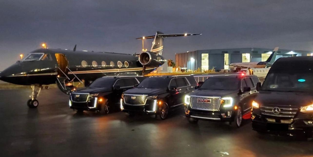 A group of cars parked in front of an airplane.