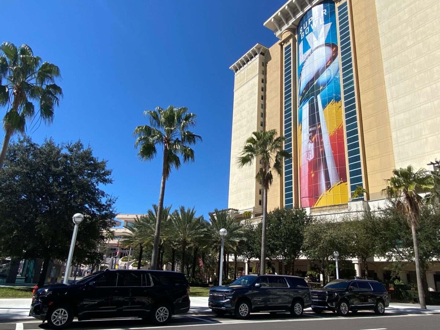 A large building with palm trees and cars parked on the side of it.