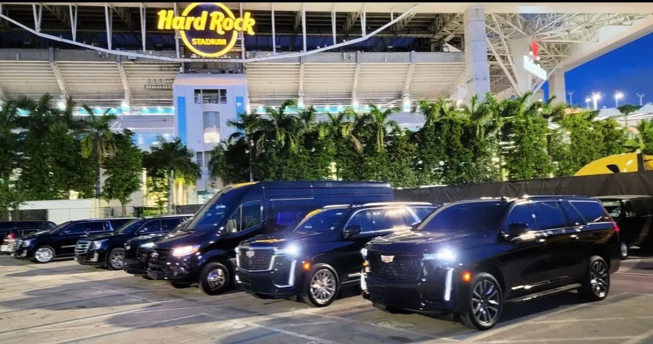 A group of black vans parked in front of hard rock stadium.