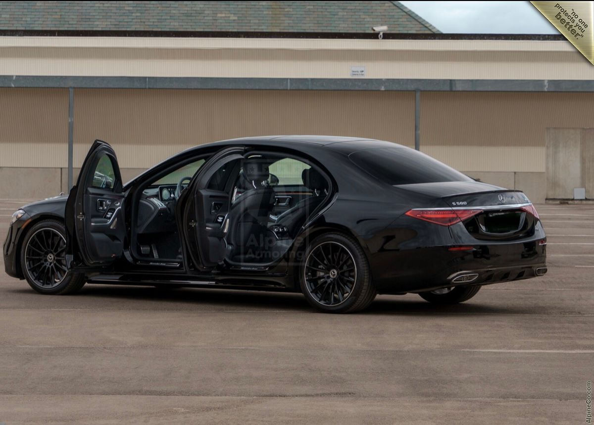 A black car with its doors open parked in the parking lot.