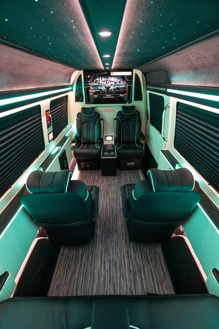 A view of the inside of a bus with seats and a tv on.