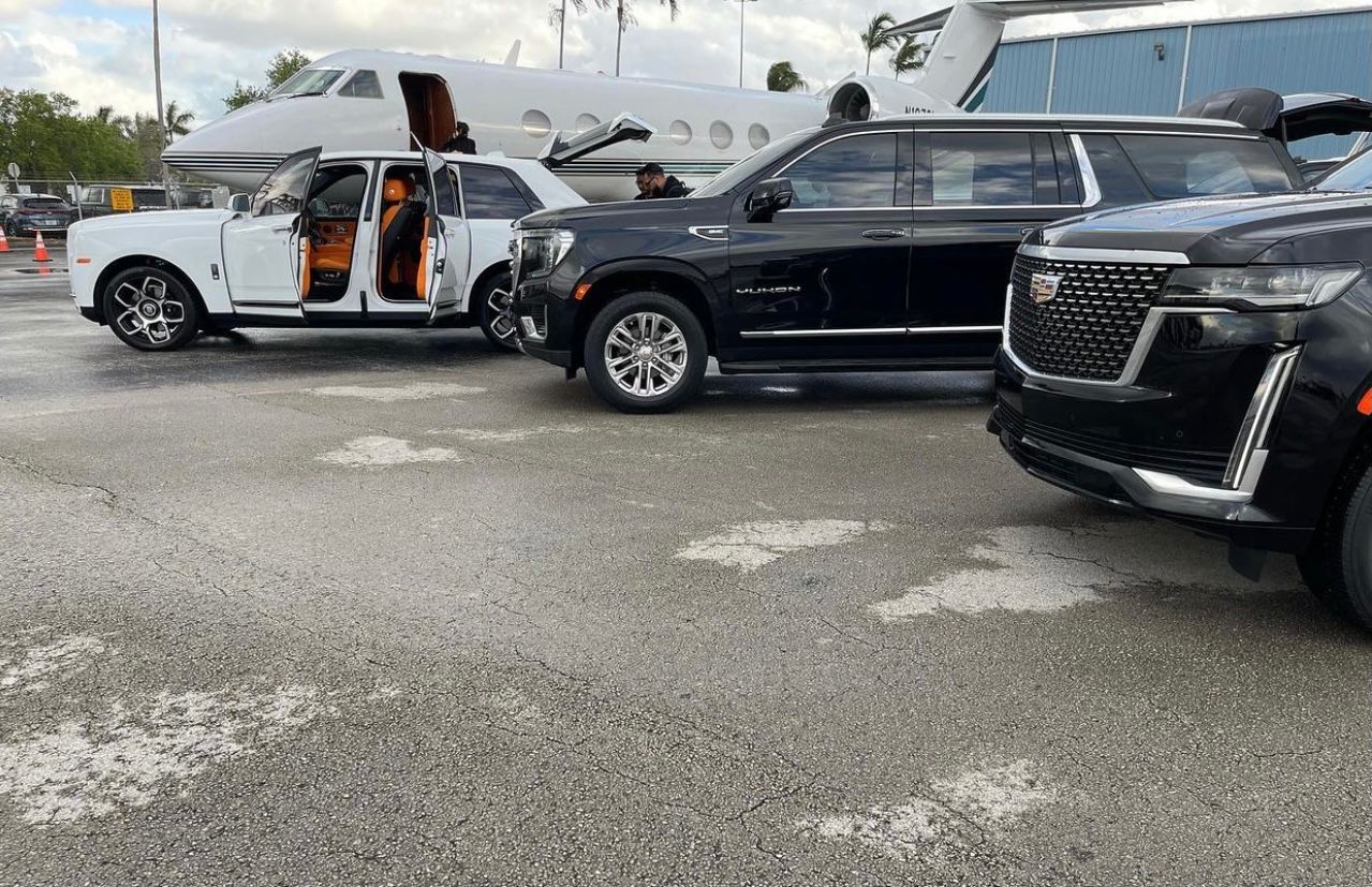 A black and white car parked in front of an airplane.