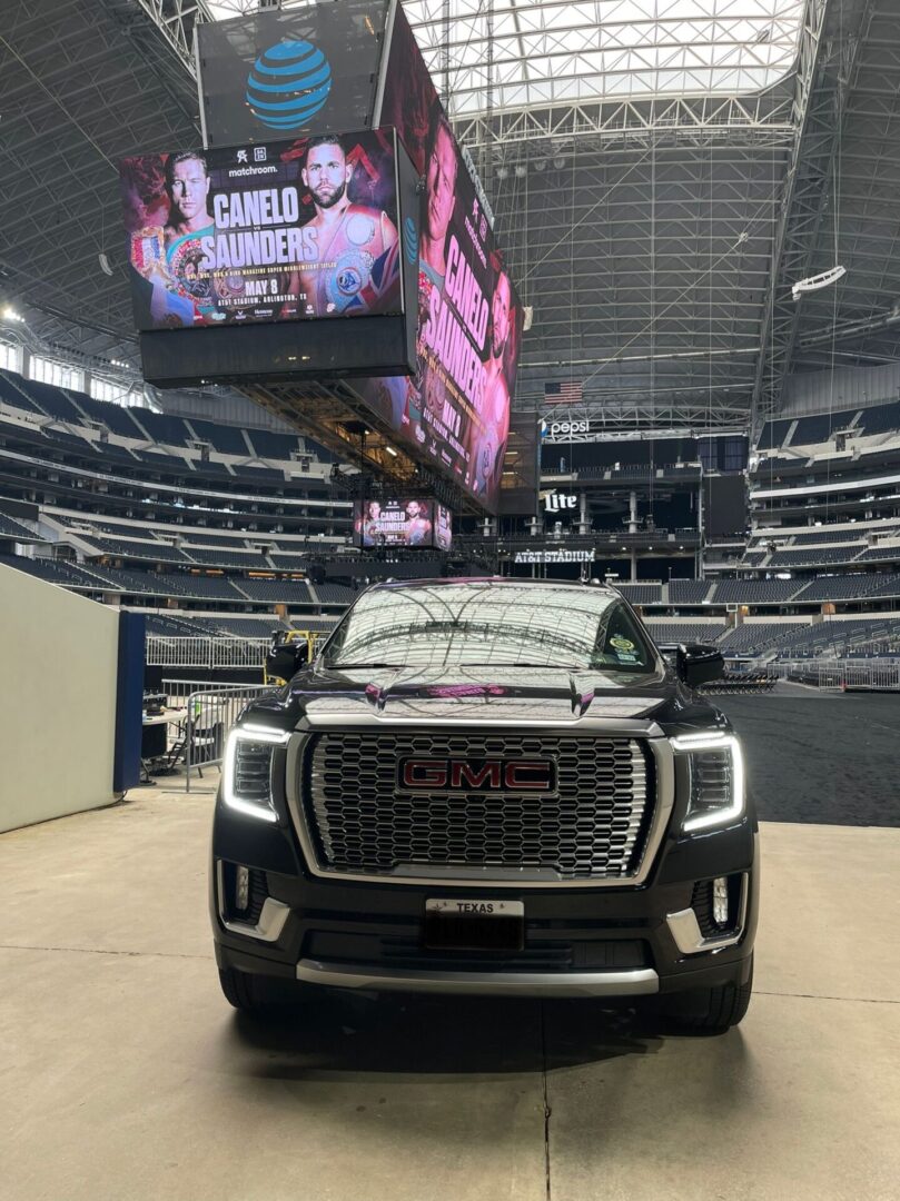 A black truck parked in front of a stadium.