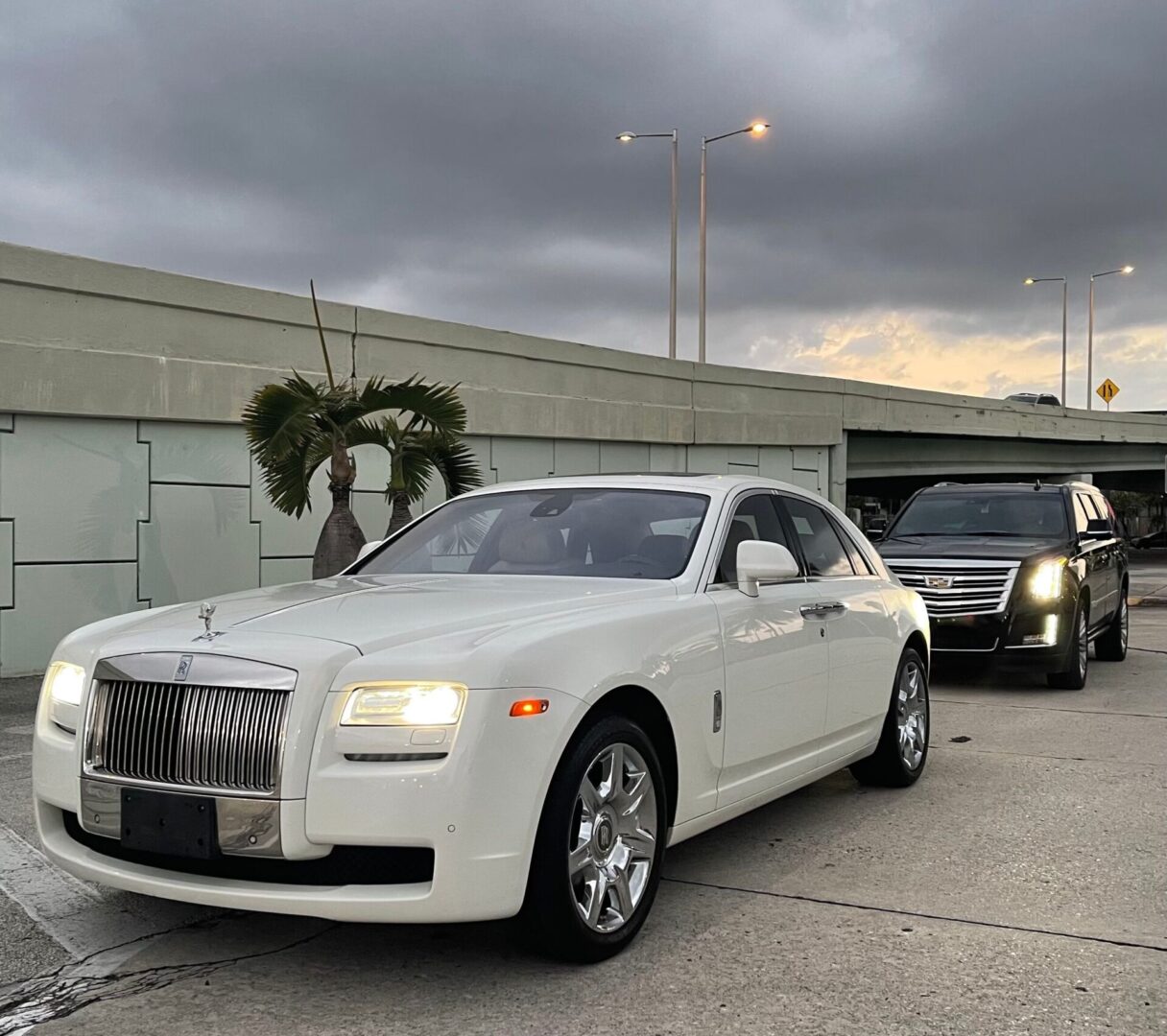 A white rolls royce parked on the side of a road.