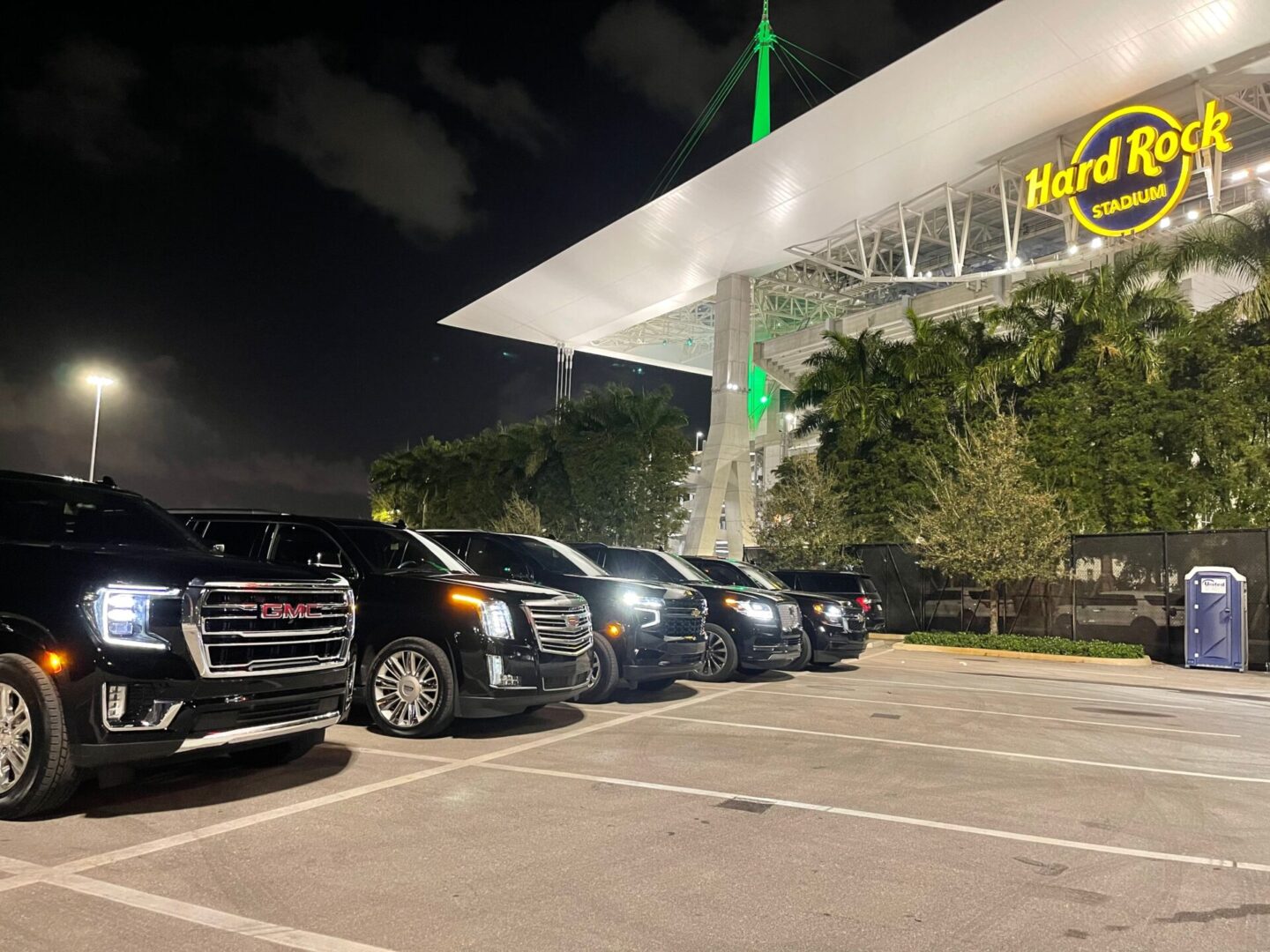 A group of cars parked in a parking lot at night.