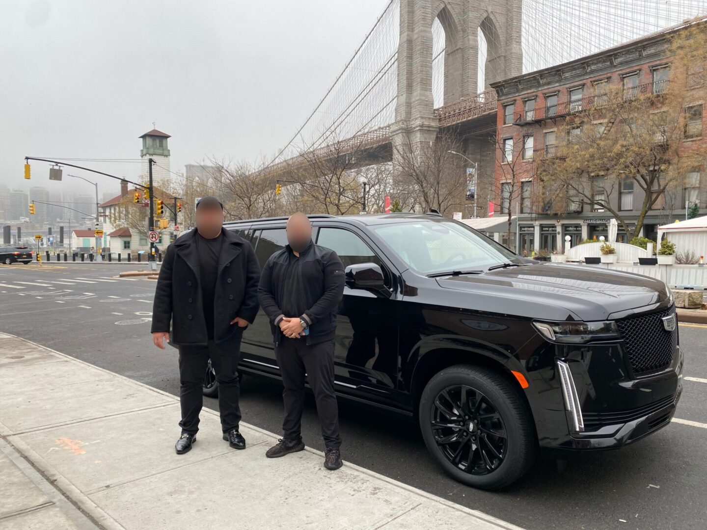 Two men standing next to a black car.